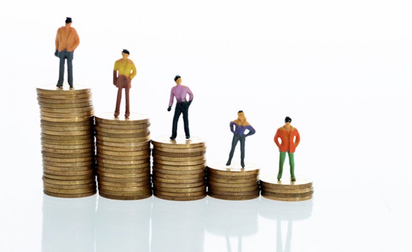 Figurines standing on stack of coins to show salary grades